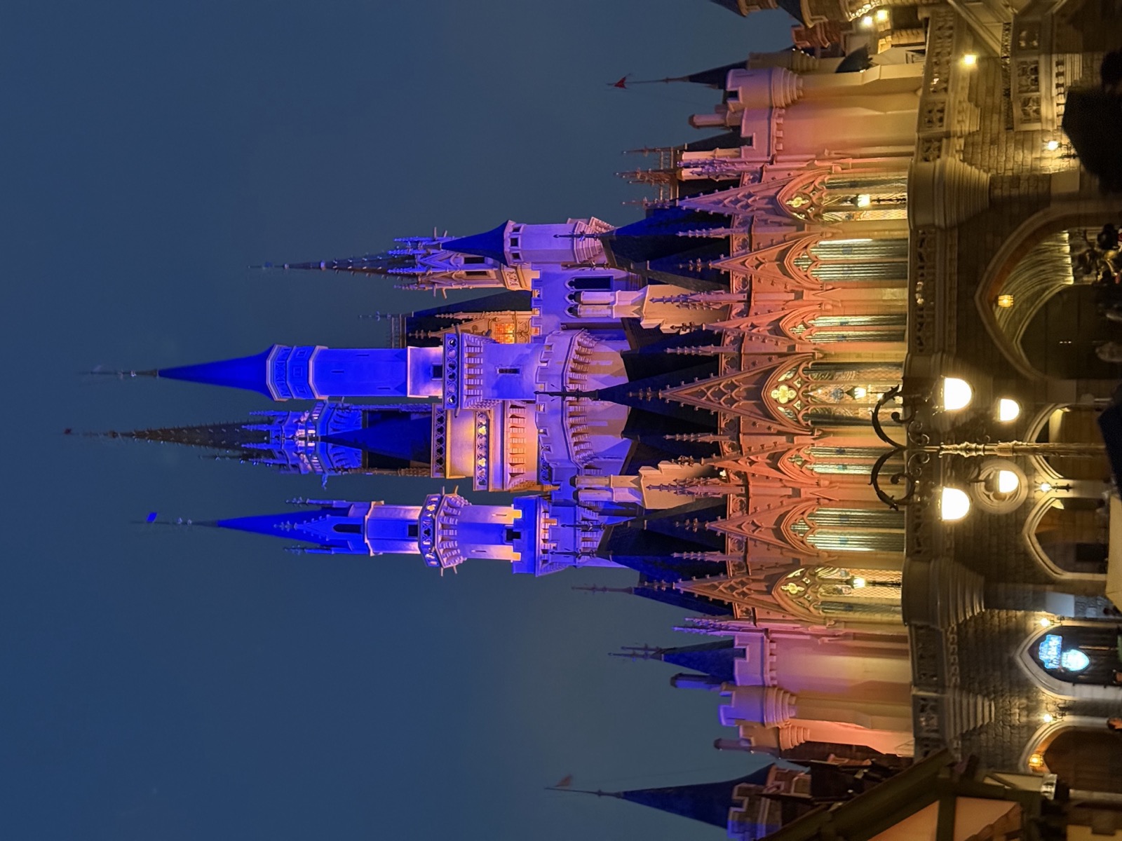 Cinderella Castle at Tokyo Disneyland lit up in blue and gold at twilight